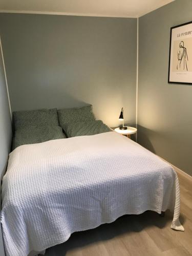 1 dormitorio con 1 cama con colcha blanca en Nymoen Apartment, Kvaløya, en Tromsø