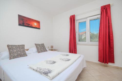 - une chambre avec un lit blanc avec des rideaux rouges et une fenêtre dans l'établissement Dusica apartments, à Tribunj