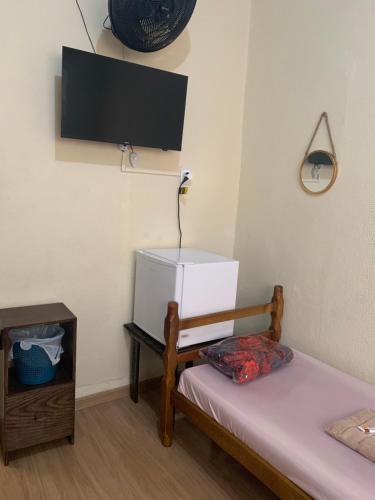 a room with a bed and a tv on the wall at Pousada Boa Noite in Atibaia