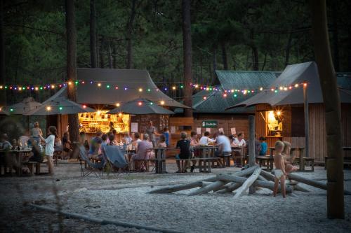 un grupo de personas sentadas en un bar por la noche en Huttopia Lac d'Aiguebelette, en Saint-Alban-de-Montbel