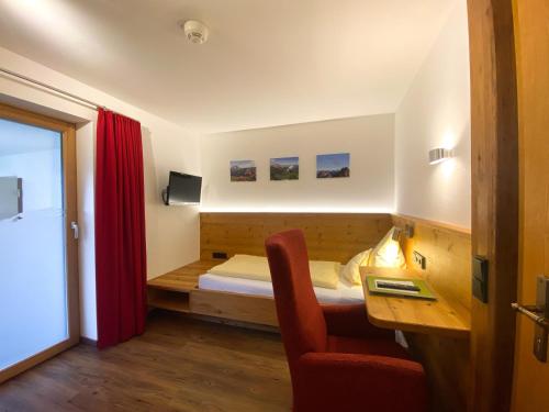 a bedroom with a bed and a desk and a chair at Hotel Alpensonne in Riezlern