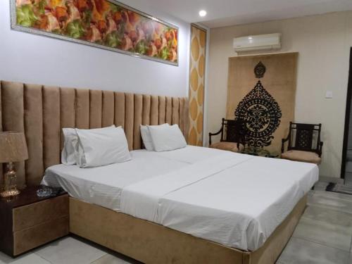 a bedroom with a large white bed and two chairs at Helen One Hotel in Lahore