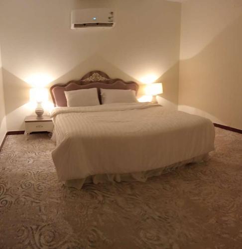 a bedroom with a large bed with two lamps at Classy Apartment in Buraydah