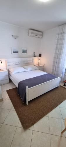 a bedroom with a large white bed with a rug at Apartments Hani in Postira
