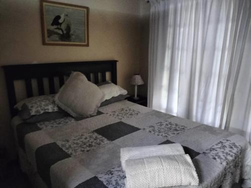 een slaapkamer met een bed met een dekbed en kussens bij ADS Overnight Accommodation in Richards Bay