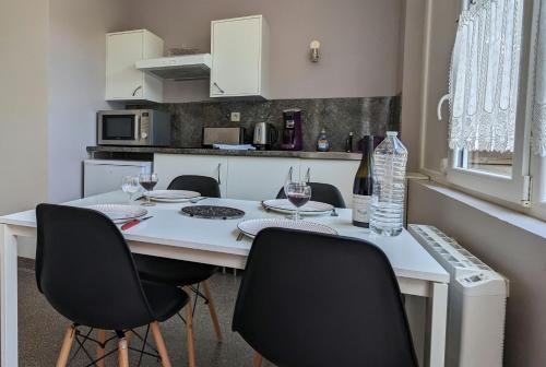 een keuken met een tafel met stoelen en wijnglazen bij Les gîtes de Cour Rémond in Villers-la-Faye