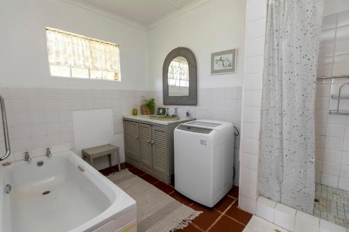 a white bathroom with a tub and a sink at Granny Smith Cottage in Himeville