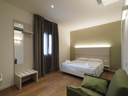 een slaapkamer met een bed, een bank en een spiegel bij Relais Dogana Rooms in Moniga