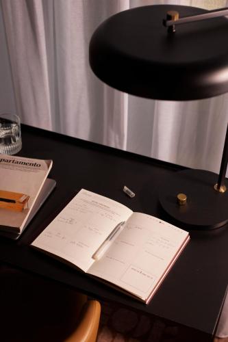 an open book on a desk with a lamp at Le Parchamp, a Tribute Portfolio Hotel, Paris Boulogne in Boulogne-Billancourt