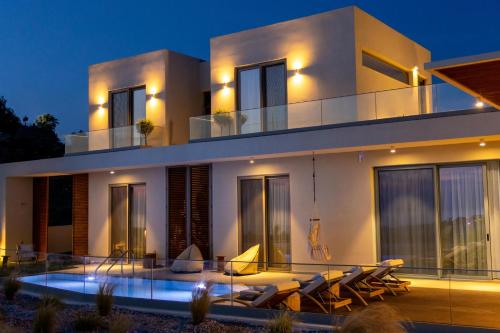 une grande maison blanche avec une piscine la nuit dans l'établissement Sueno Villas, à Panormos Rethymno