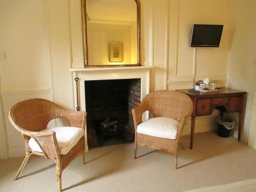 een kamer met 2 stoelen, een tafel en een spiegel bij Old Manor House in Shepperton