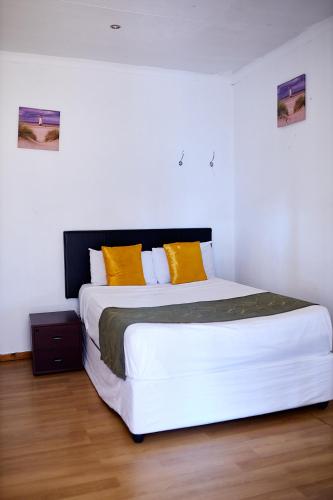a bedroom with a large white bed with yellow pillows at Airport Royal Guest House in Kempton Park