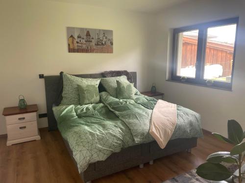 Schlafzimmer mit einem Bett mit grüner Bettwäsche und einem Fenster in der Unterkunft Ferienhaus Herre in Freinberg