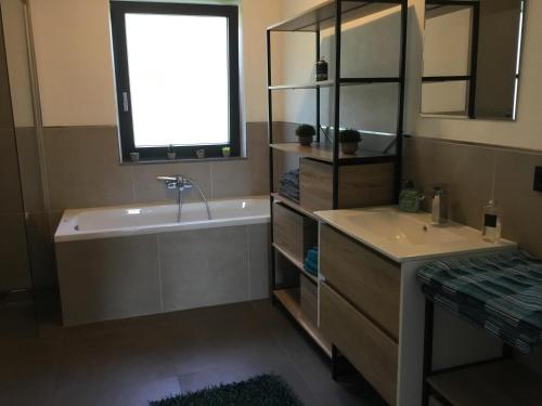 bagno con vasca, lavandino e finestra di Ferienhaus Herre a Freinberg