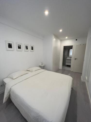 um quarto branco com uma grande cama branca em Neptun guest house em Queluz