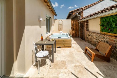a patio with a table and a bath tub at l'Alcove - SPA&SAUNA privé - Oliveraie d'Eurocentre in Castelnau-dʼEstrétefonds
