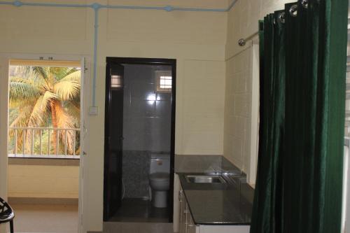 a bathroom with a toilet and a green shower curtain at San Unik Homestay in Nilambūr