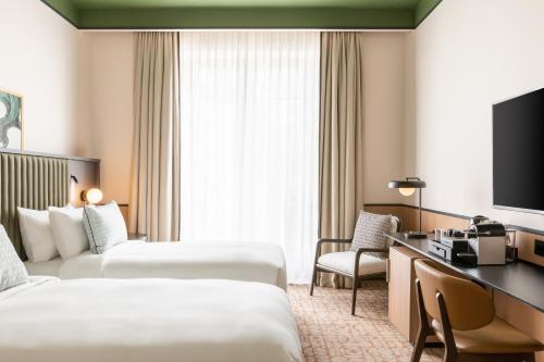 a hotel room with two beds and a television at Le Parchamp, a Tribute Portfolio Hotel, Paris Boulogne in Boulogne-Billancourt