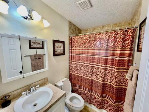 La salle de bains est pourvue d'un lavabo, de toilettes et d'une douche. dans l'établissement Cozy Modest Home near Universal Studios/VolcanoBay, à Orlando