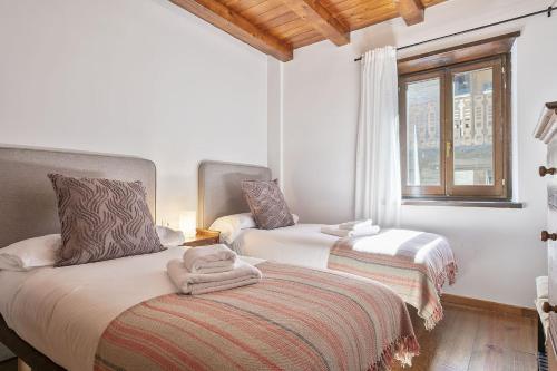 a bedroom with two beds and a window at Luderna - Apartamento Centelha in Tredós