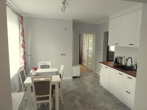 a kitchen with white cabinets and a table and chairs at Apartament Magnolia in Muszyna