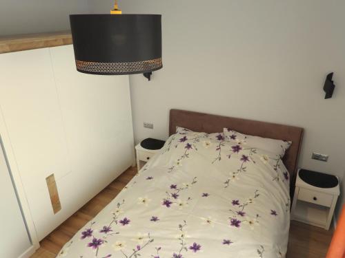 a bedroom with a bed with purple flowers on it at Apartament Magnolia in Muszyna