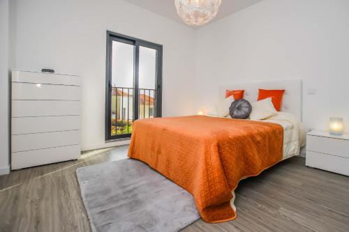um quarto com uma cama com um cobertor laranja e uma janela em Solar da Rochinha Magnifico Apt 2 Quartos Funchal no Funchal