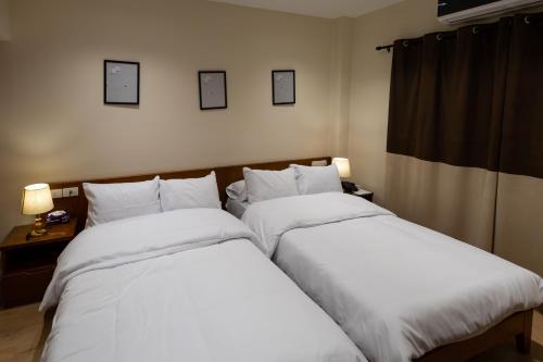 two beds in a hotel room with white sheets at Marron studios 1 new in Cairo