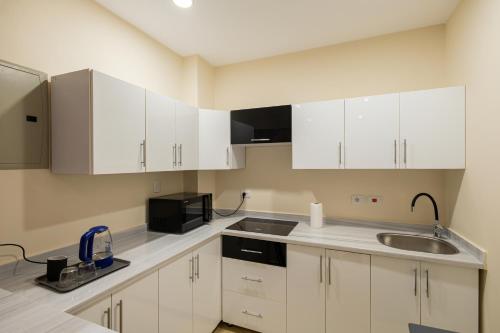 カイロにあるMarron studios 1 newの白いキャビネット、シンク、電子レンジ付きのキッチンが備わります。