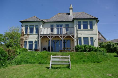 a bench in front of a large house at Island View at White Horses, Bantham, South Devon - with glorious sea views in Bantham