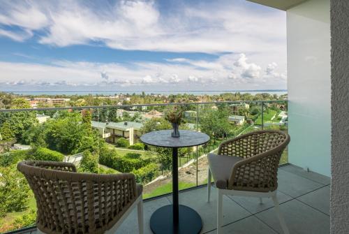 a balcony with a table and chairs and the ocean at Hotel Vinifera Wine & Spa 5 Stars Superior in Balatonfüred