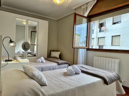 Un dormitorio con dos camas y una ventana. en Apartamentos Playa del Sable, en Isla