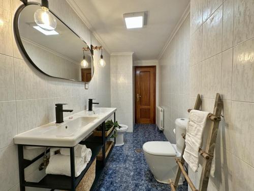 Un baño con lavabo, inodoro y espejo. en Apartamentos Playa del Sable, en Isla