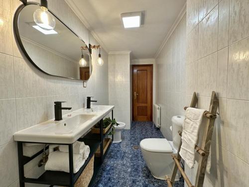 a bathroom with a sink and a toilet and a mirror at Apartamentos Playa del Sable in Isla