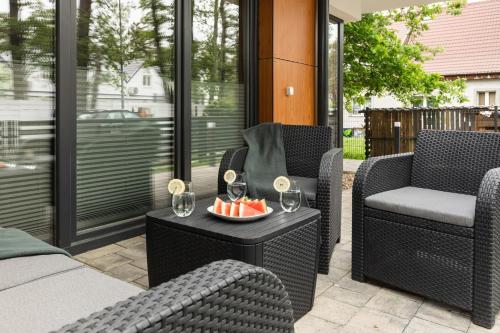 un patio con 2 sillas y una mesa con copas de vino. en Luxurious Little Laguna Apartments SPA & Gym by Renters Prestige, en Międzywodzie
