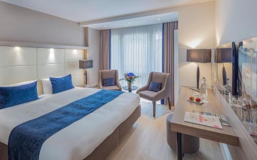 フライブルク・イム・ブライスガウにあるザ アレックス ホテルの大きなベッドとデスクが備わるホテルルームです。