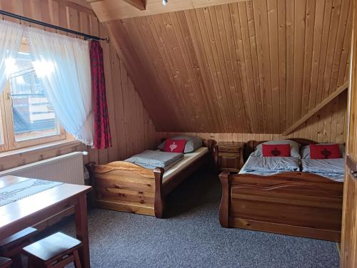 a room with two beds in a wooden cabin at Domek góralski Toporówka in Murzasichle