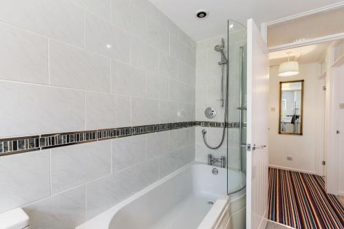 ein weißes Badezimmer mit Badewanne und Dusche in der Unterkunft Merlins Gardens in Tenby