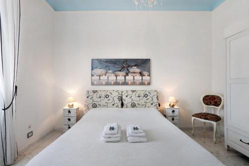 een slaapkamer met een wit bed en 2 handdoeken bij Marta in Portovenere
