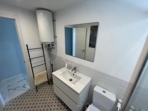 a bathroom with a sink and a mirror and a toilet at Playa Romana Altamar in Alcossebre