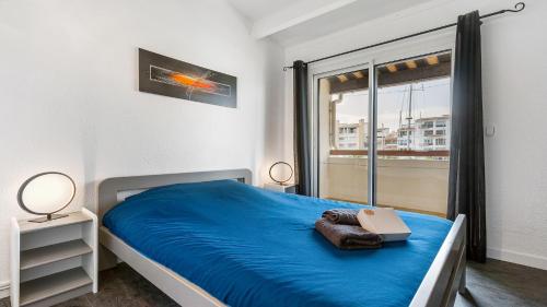 une chambre avec un lit avec des draps bleus et une fenêtre dans l'établissement SouthMarina by POM, vue bateaux, terrasse, parking, au Cap d'Agde
