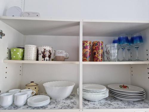 a white pantry with plates and bowls on shelves at Casa Cristina in Pécs