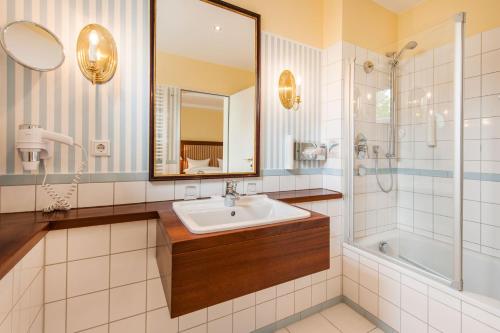 ein Bad mit einem Waschbecken, einer Dusche und einem Spiegel in der Unterkunft Hotel Birke, Ringhotel Kiel in Kiel