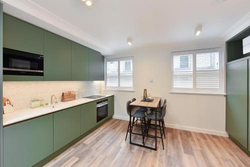 a kitchen with green cabinets and a stool in it at James Street Serviced Apartments by Globe Apartments in London