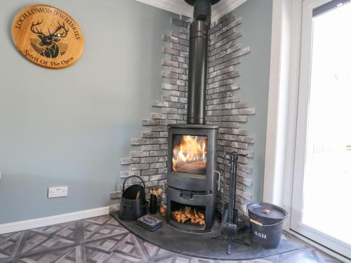 a fireplace in a room with a stone wall at Ben View in Arrochar