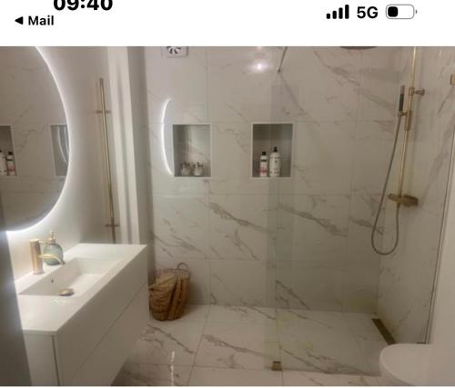 La salle de bains blanche est pourvue d'une douche et d'un lavabo. dans l'établissement charmigt radhus i centrala Göteborg, à Göteborg