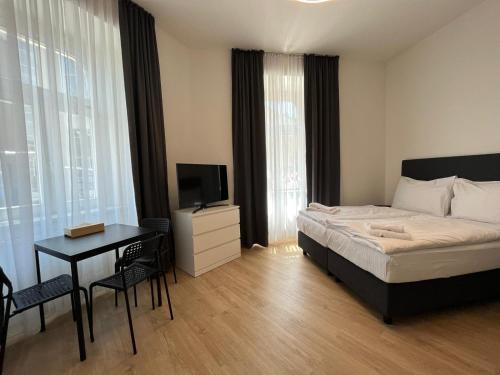 Figaro Suites في براغ: غرفة نوم بسرير ومكتب وتلفزيون