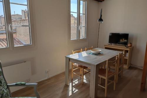 comedor con mesa, sillas y TV en Charming 48 m apartment in downtown Avignon, en Aviñón