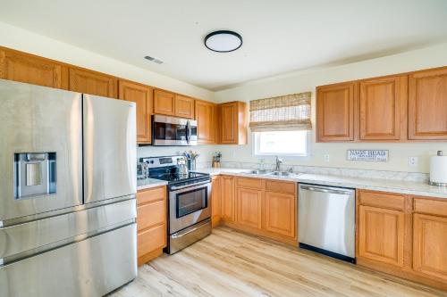 a kitchen with wooden cabinets and stainless steel appliances at Nags Head Vacation Rental with Hot Tub Near Beach! in Nags Head