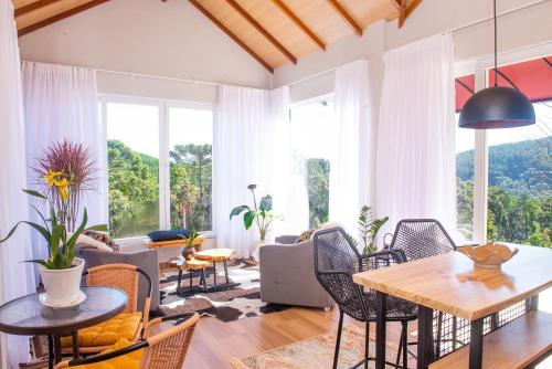 a living room with a table and chairs and windows at Timber Lodge Camanducaia in Monte Verde